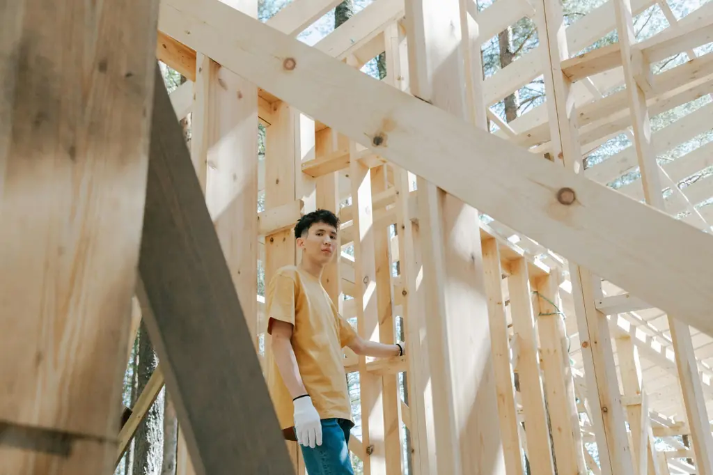 Worker assembling a wooden frame structure outdoors, highlighting construction craftsmanship and precision