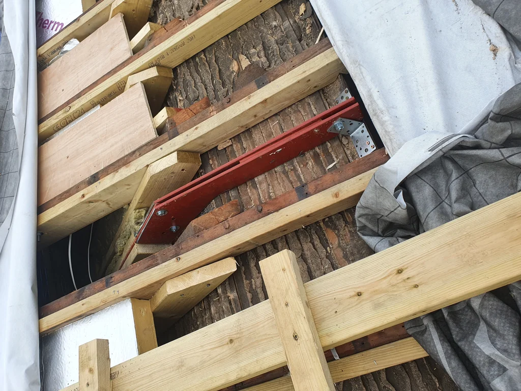 Timber joist structure with metal support bracket installed as part of loft floor reinforcement