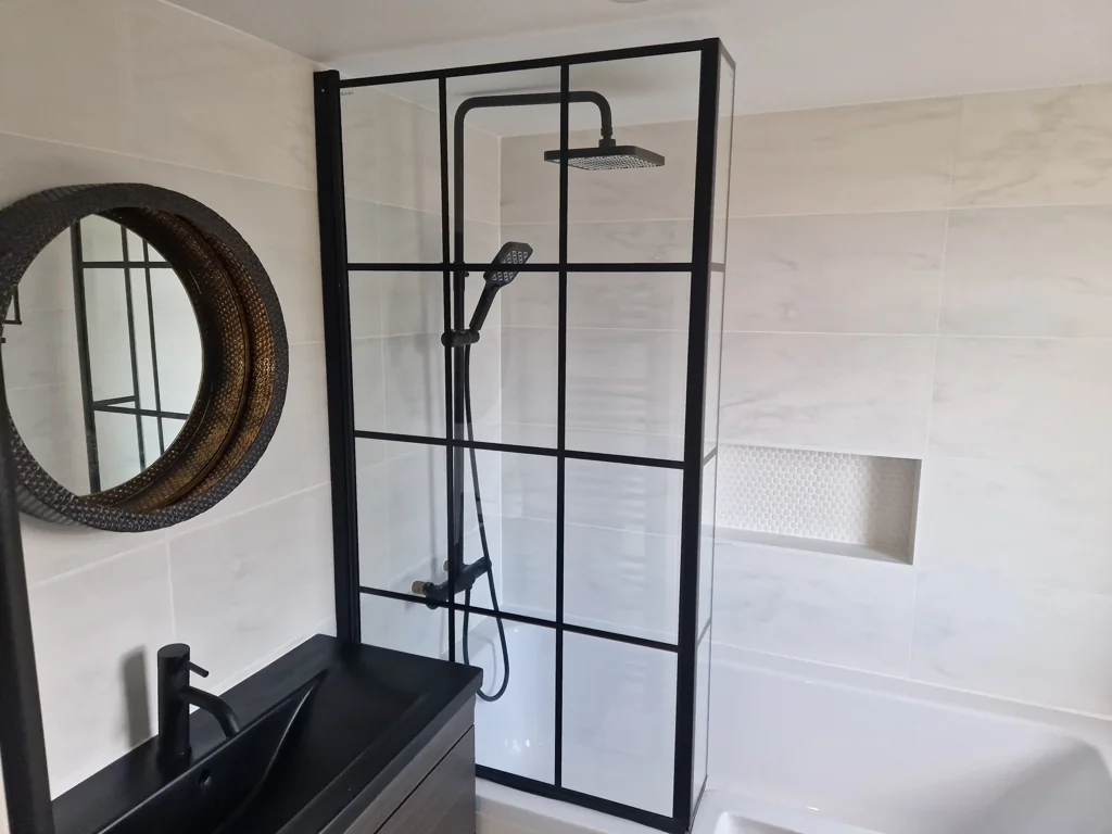 Completed modern bathroom with black framed shower screen, wall tiles, recessed shelf and vanity unit